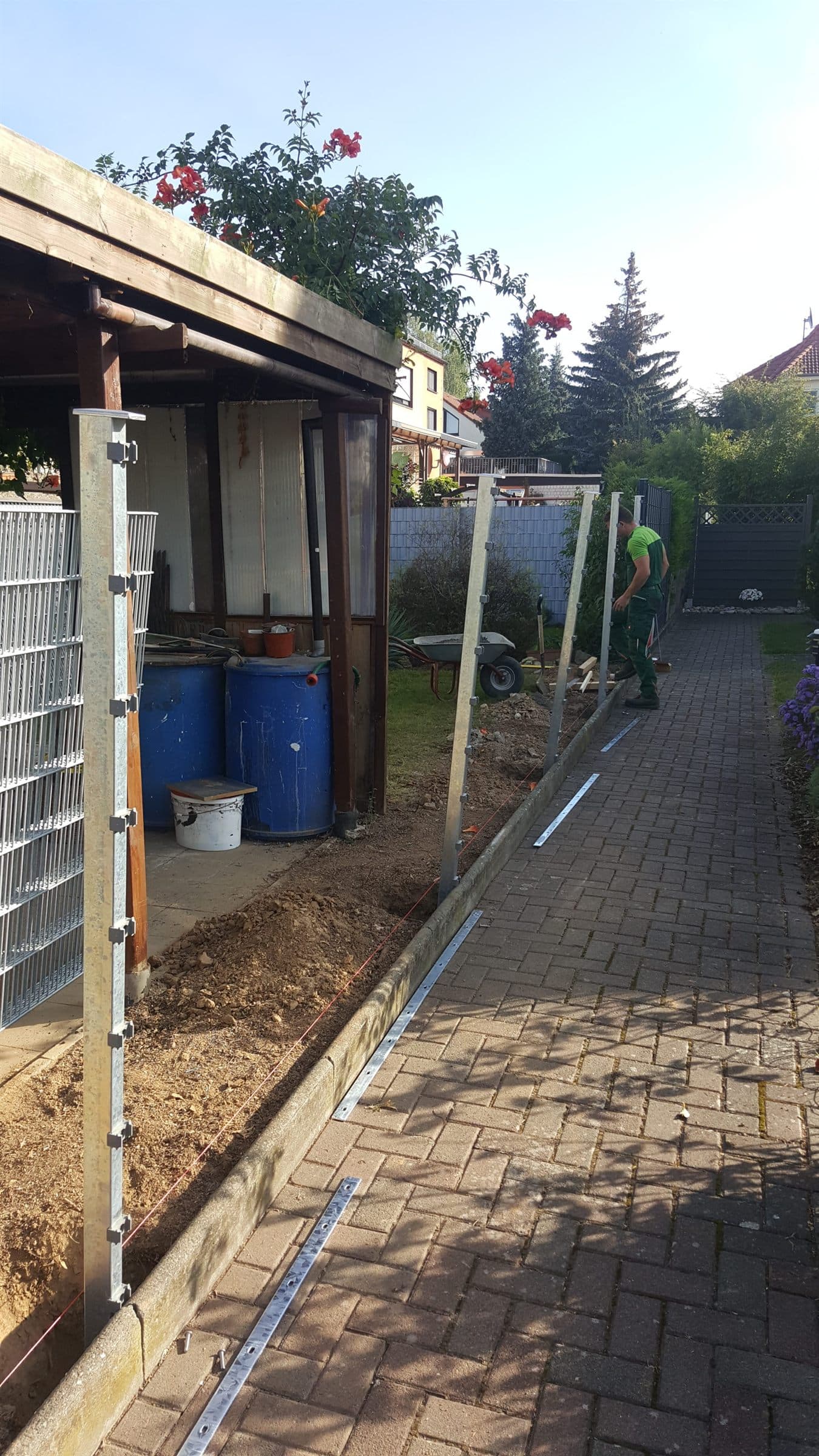 Gesetzte Zaunpfosten entlang eines gepflasterten Weges